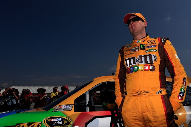 Kyle Busch, driver of the #18 M&M's Toyota, stands next to his car on the grid after qualifying at Talladega fall race 2012