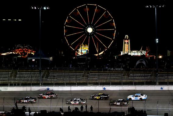 Cars race past the carnival during the NASCAR Nationwide Series 