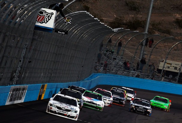 Joey Logano, driver of the #18 GameStop/Epic Mickey2 Toyota, takes the checkered flag as he crosses the finish line to win the NASCAR Nationwide Series Great Clips 200 at Phoenix