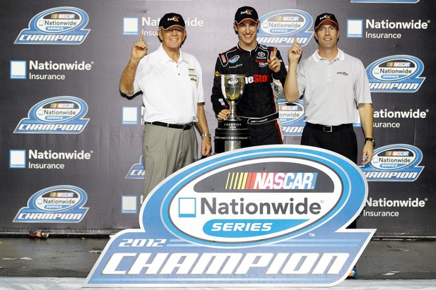 Team owner Joe Gibbs, Joey Logano, driver of the #18 GameStop/Afterglow Toyota, and J.D. Gibbs celebrate after winning the owners point championship after the NASCAR Nationwide Series Ford EcoBoost 300 at Homestead