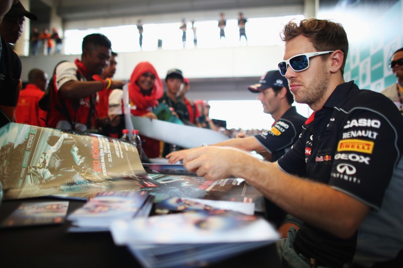 Sebastian Vettel of Germany and Infiniti Red Bull Racing signs autographs for fans before the Malaysian Formula One Grand Prix at the Sepang Circuit on March 24, 2013 in Kuala Lumpur, Malaysia. 