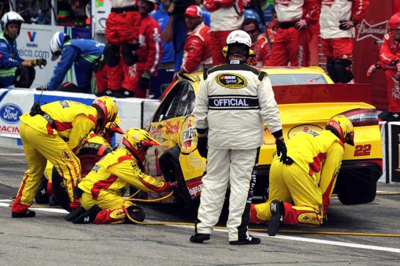 Crew members work on the car of Joey Logano, driver of the #22 Shell-Pennzoil/AAA Ford, in the pits after cutting a tire during the NASCAR Sprint Cup Series Camping World RV Sales 301 at New Hampshire Motor Speedway on July 14, 2013 in Loudon, New Hampshire.