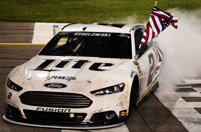 Brad Keselowski, driver of the #2 Miller Lite Ford, celebrates with the American flag and a burnout after winning the NASCAR Sprint Cup Series Federated Auto Parts 400 at Richmond International Raceway on September 6, 2014 in Richmond, Virginia. 
