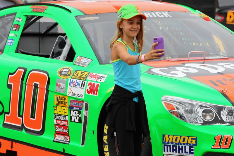 A young fan takes a selfie in front of Danica Patrick's #10 GoDaddy.com Chevrolet before the NASCAR Sprint Cup Series Sylvania 300 at New Hampshire Motor Speedway on September 21, 2014 in Loudon, New Hampshire. 