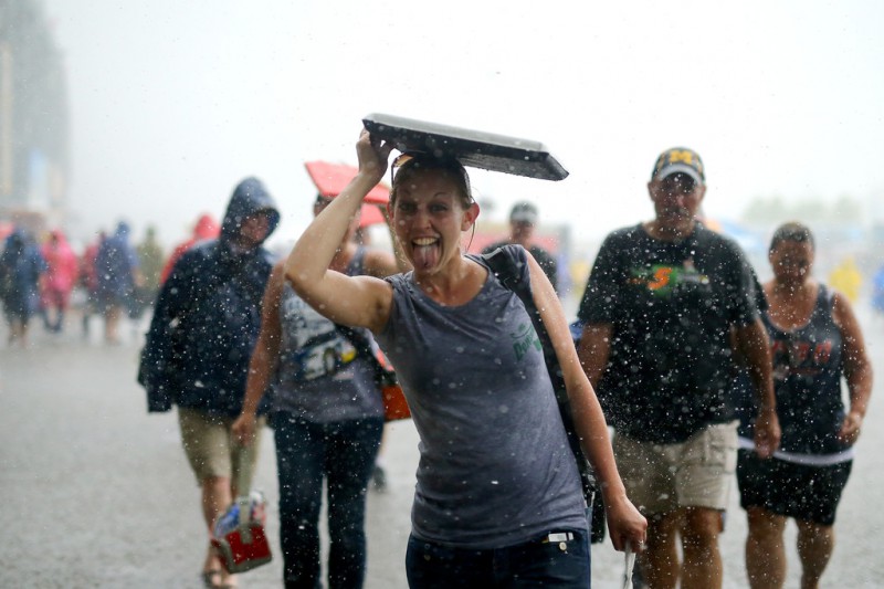 Race fans walk under the grandstands as it rains during the NASCAR Sprint Cup Series Quicken Loans 400 at Michigan International Speedway on June 14, 2015 in Brooklyn, Michigan.