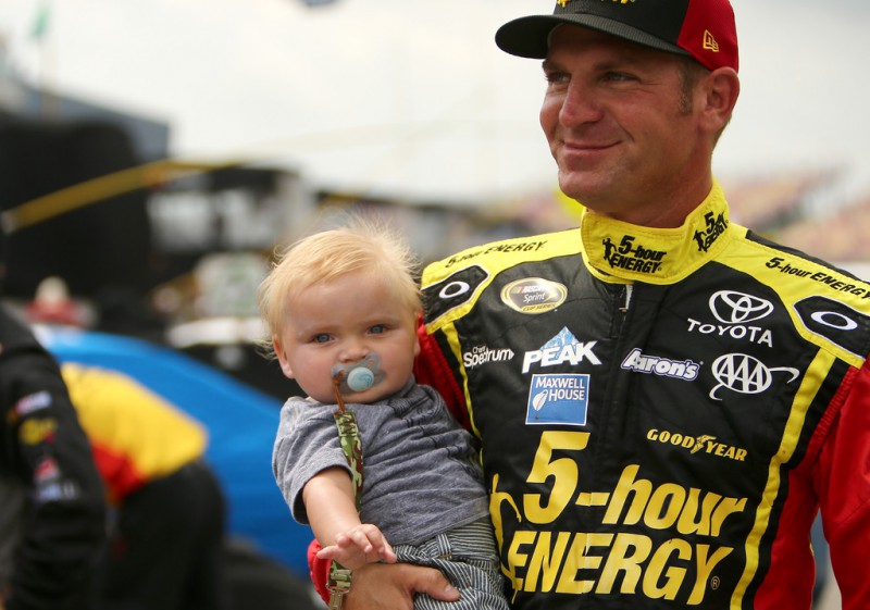 Clint Bowyer, driver of the #15 Cherry 5-hour ENERGY benefiting Special Operations Warrior Foundation Toyota, holds his son Cash Aaron Bowyer prior to the NASCAR Sprint Cup Series Quicken Loans 400 at Michigan International Speedway on June 14, 2015 in Brooklyn, Michigan.