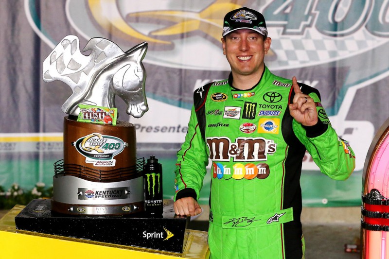 Kyle Busch, driver of the #18 M&M's Crispy Toyota, poses with the winner's trophy in Victory Lane after winning the NASCAR Sprint Cup Series Quaker State 400 presented by Advance Auto Parts at Kentucky Speedway on July 11, 2015 in Sparta, Kentucky. 